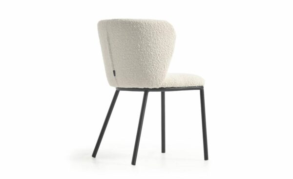 Cadeira Ciselia Branco, estofada com tecido efeito cordeiro na cor branco. Estrutura de metal com acabamento pintado preto mate para um design moderno e elegante.